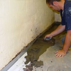 A basement waterproofer installing a perimeter drain system in Taylor