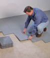 Contractors installing basement subfloor tiles and matting on a concrete basement floor in Clinton Township, Michigan