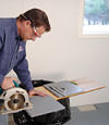 installing a waterproof vapor barrier on a basement floor to prepare for basement carpeting in a Detroit home